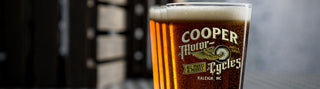 full pint glass with personalized motorcycle design, shining in sun from garage workshop window