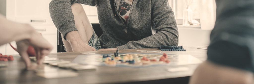 A family plays a board game at their dining room table.